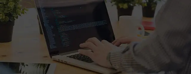 ノートパソコンでコードを書いている男性